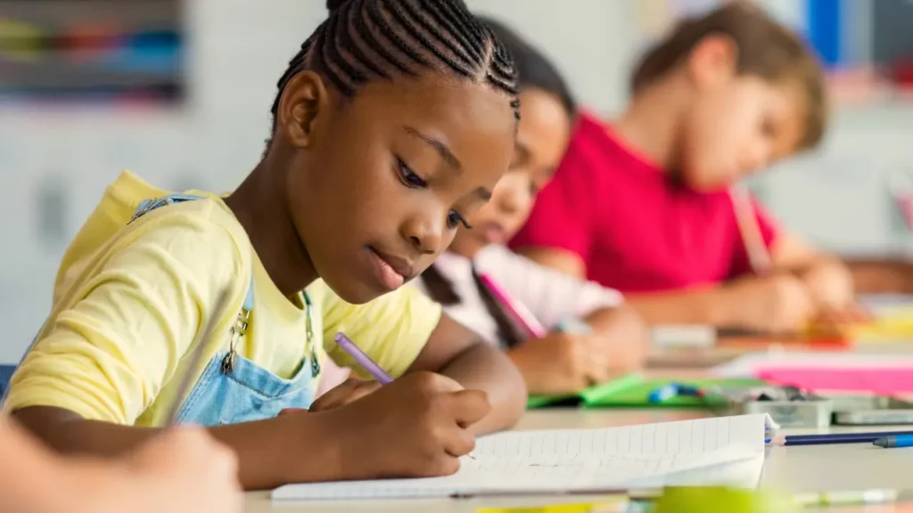Menina estudando com auxílio material escolar.